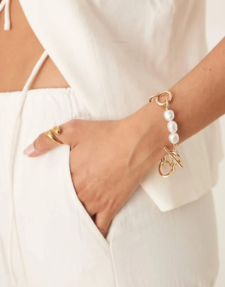 ASOS ASOS DESIGN chain bracelet with t-bar and faux pearl details in gold tone from ASOS