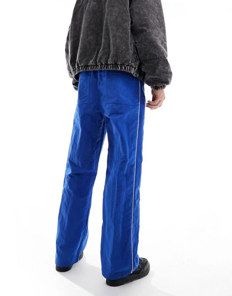 ASOS ASOS DESIGN baggy nylon track pants in blue with white piping 4