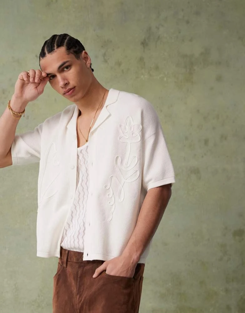 ASOS ASOS DESIGN relaxed boxy fit knitted button through polo with floral embroidery in ecru 1