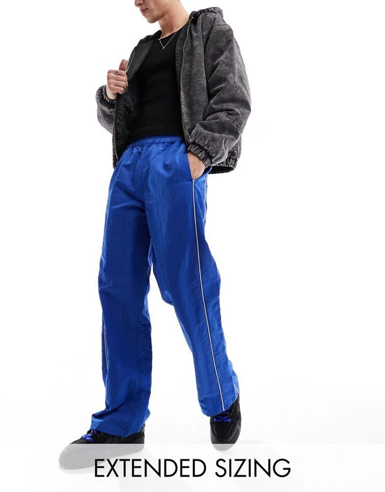 ASOS ASOS DESIGN baggy nylon track pants in blue with white piping 1